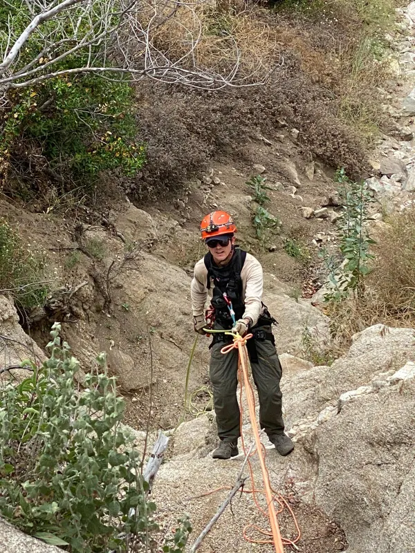 A rescuer rigging a litter on a steep embankment