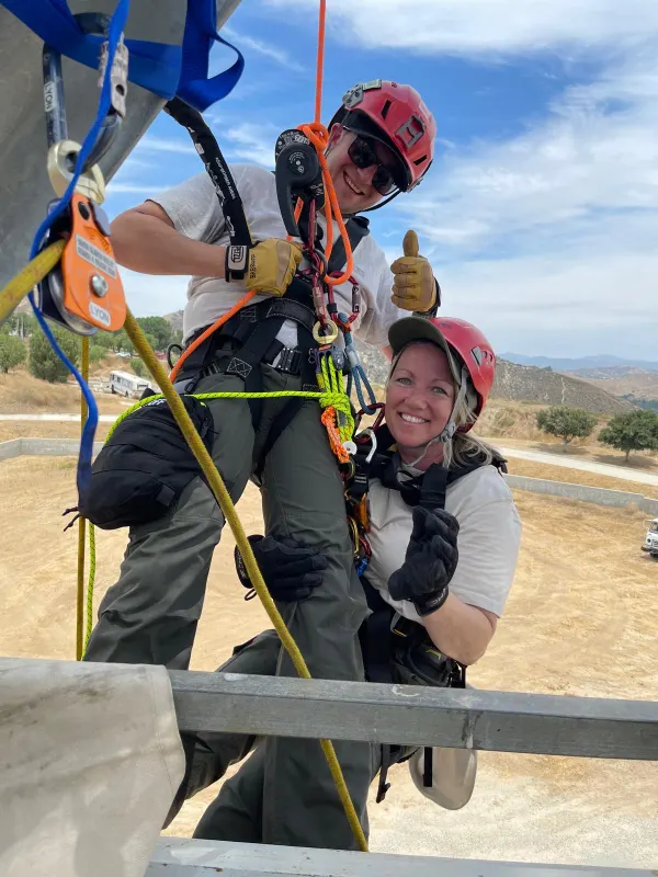 Two rescuers on a rope system, one giving a thumbs up
